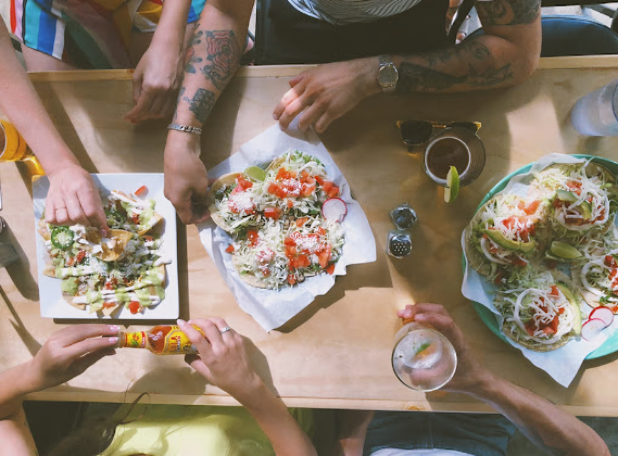 Friends sharing tacos, nachos, and drinks around a table at Taqueria Portland